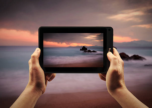 Person holding a smartphone in hand making a picture of a beach