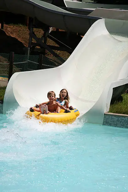 Two really cute young children take the plunge on a super fast water slide.  Lots of copy space!!! 