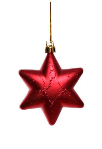 DSLR studio shot of a Red Christmas star shaped decorations on a white background. The star is attached by a golden thread. 