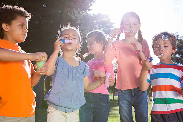 istock Little friends blowing bubbles in park 471114108