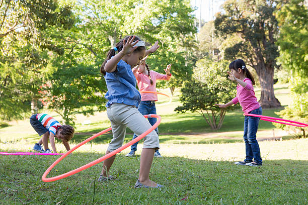 istock Little friends playing with hula hoops in park 471114124