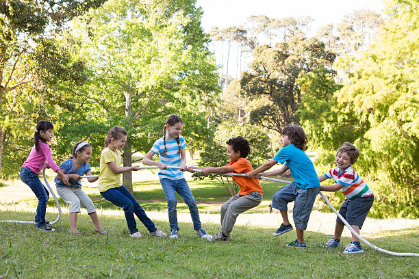 bambini avendo un tiro alla fune al parco - tug o war foto e immagini stock