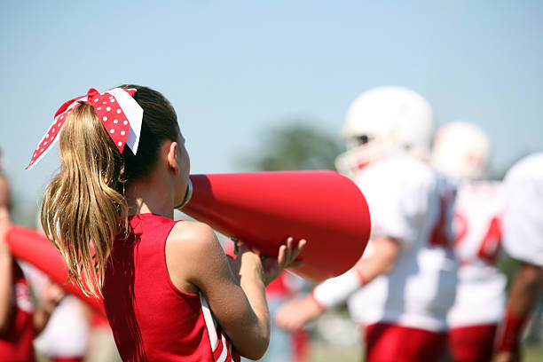 Cheerleader with Megaphone cheers for her Football Team Cute Cheerleader supports her team by cheering through her Megaphone from the sidelines. Focus on Cheerleader. cheerleader photos stock pictures, royalty-free photos & images