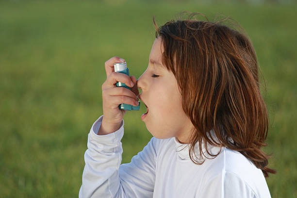 istock Little girl using her asthma inhaler outside 471117499