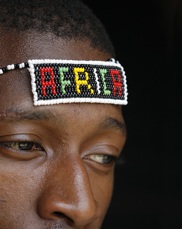 A young African man wearing a beaded headband with the word 