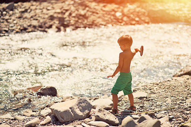 istock Little boys throwing stones at river 471122454