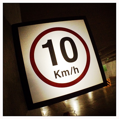 A 10 kilometre per hour speed limit sign in a underground car park. Shot with an iPhone.