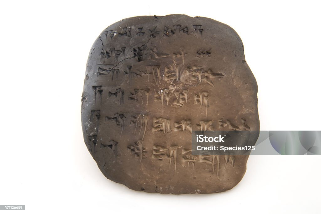 Cuneiform tablet isolated on white A tablet of cuneiform (ancient near/middle eastern "alphabet"). It is written in the Akkadian form telling the first few lines of the Descent of Ishtar to the underworld (Sumerian/Babylonian mythology) Artifact is baked clay, hence the charring on the left. Probably baked inadvertantly as the baking process is not complete or finished in a traditional glaze. Artifact is somewhat large indicating the writer has a limited proficiency with writing Akkadian. Sumerian Civilization Stock Photo