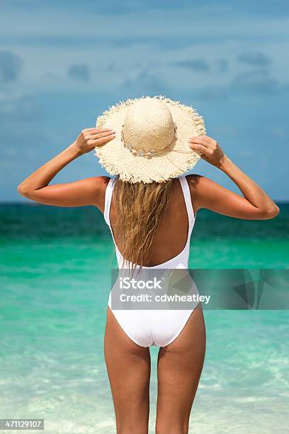 Mujer En El Sombrero En La Playa Tropical Foto de stock y más banco de imágenes de Mujeres - Mujeres, Traje de baño, Traje de baño de una pieza