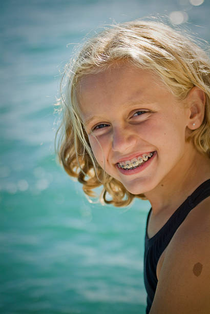 Blond girl with brace smiling at camera at a lake