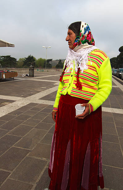 Rome, Italy - April 15, 2015: A Romany woman in bright traditional garb (long velvet skirt and flowered headscarf) begging at the EUR metro station in Rome, Italy.