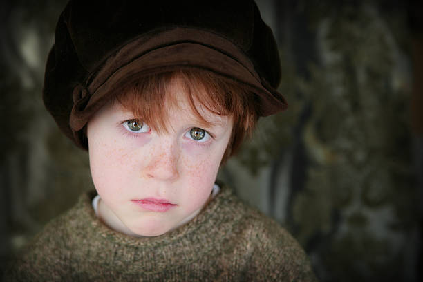 Adorable child in vintage velvet hat, in a contemplative gesture.