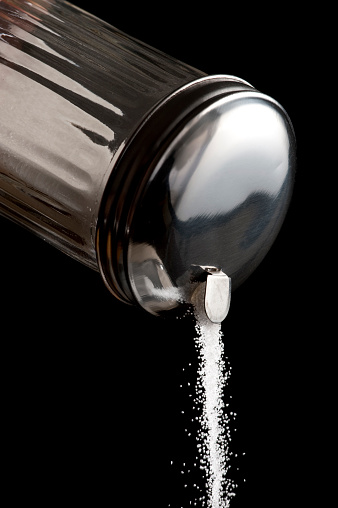 Sugar from a diner-style sugar dispenser cascades down.