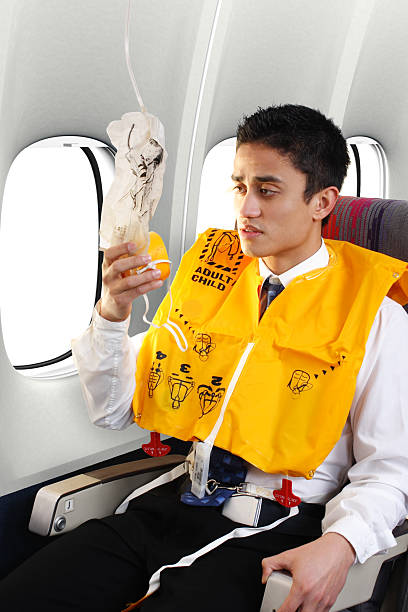 Passenger Wearing Life Vest Passenger on a commercial airliner getting ready for an emergency water landing. oxygen mask plane stock pictures, royalty-free photos & images