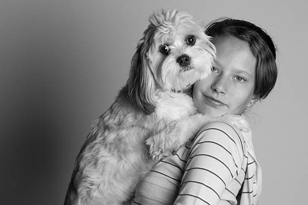 A black and white photo of a girl holding her dog.