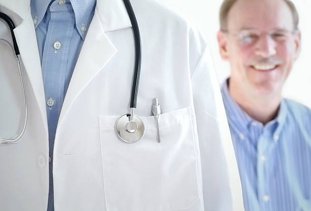 Doctor with a stethoscope and a patient smiling behind him  stock photo