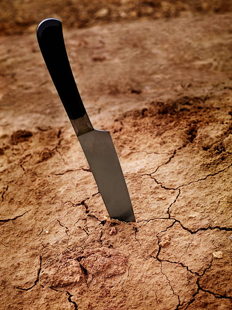 istock Bizzare Out of Context - Knife in Cracked Soil 471133161