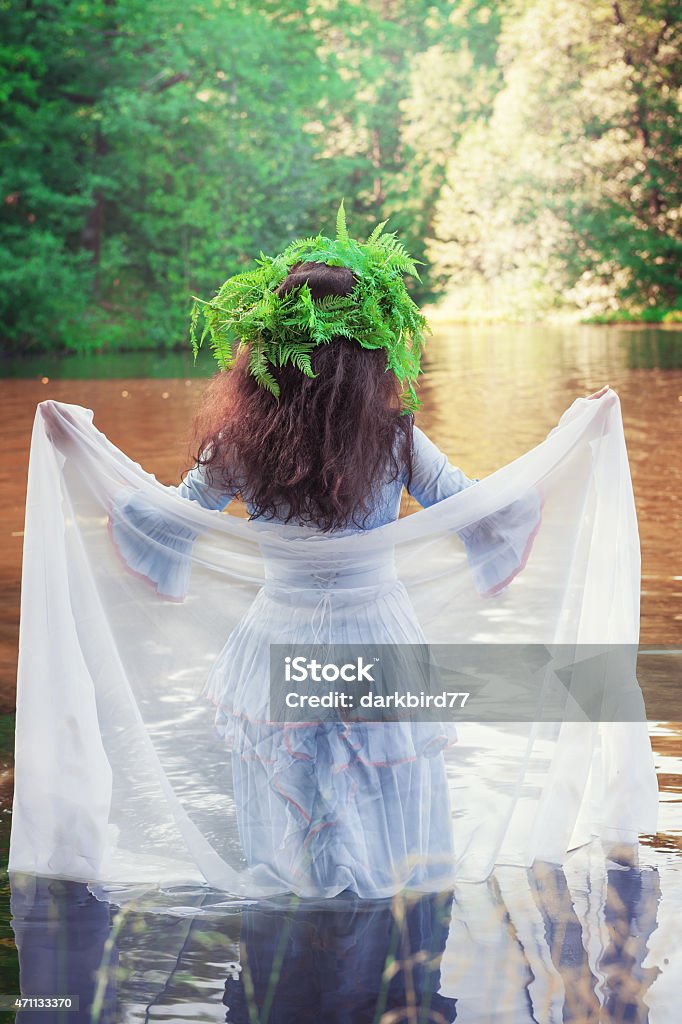 Beautiful woman with long medieval dress standing in the river Beautiful woman with long medieval dress standing in the river outdoor Fern Stock Photo