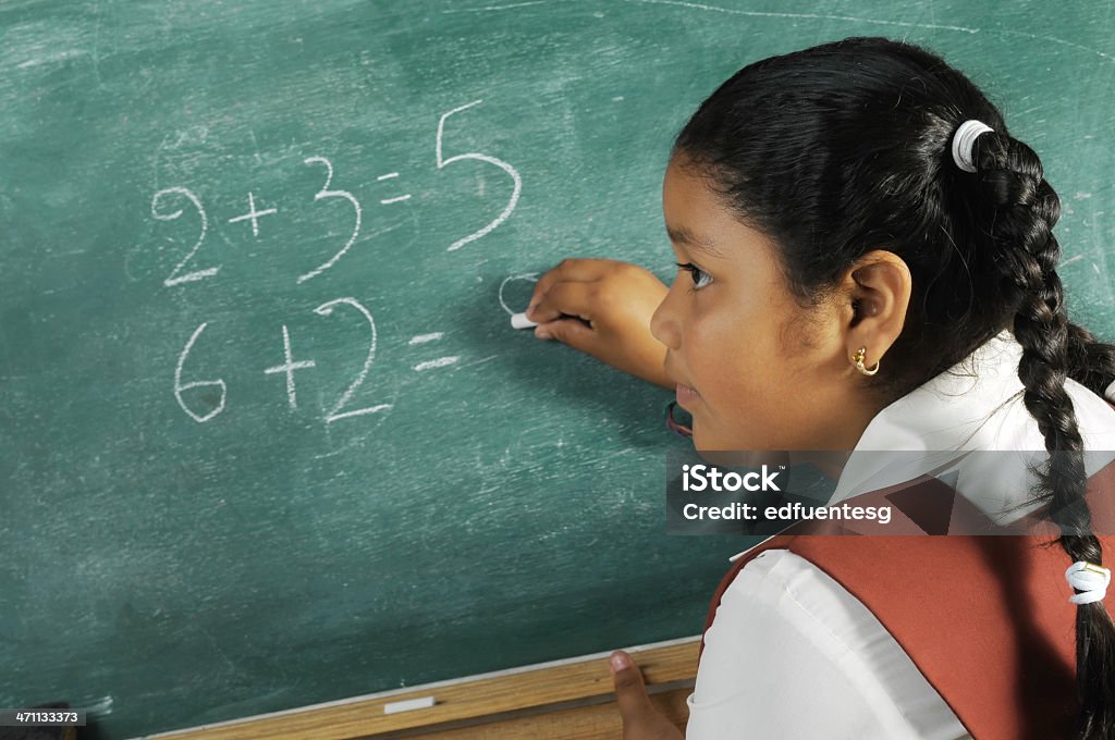 Schoolgirl solving a math problem on the chalkboard A young little girl solving a simple exercise, Latin ethnicity. El Salvador Stock Photo