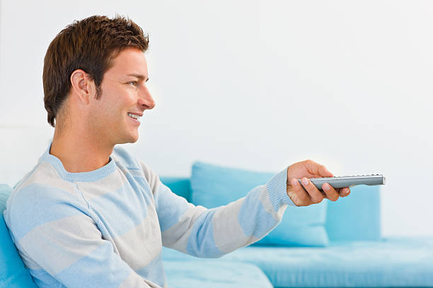 istock Smiling young woman holding remote control 471133427