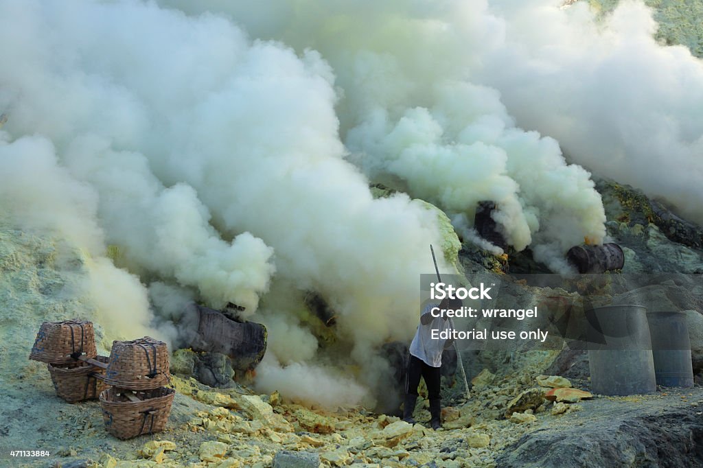 Sulphur mines Ijen Crater in East Java, Indonesia Kawah Ijen, Indonesia - August 9, 2011: Miner collects sulphur in the fumes of toxic volcanic gas at the sulphur mines in the crater of the active volcano of Kawah Ijen, East Java, Indonesia. 2015 Stock Photo
