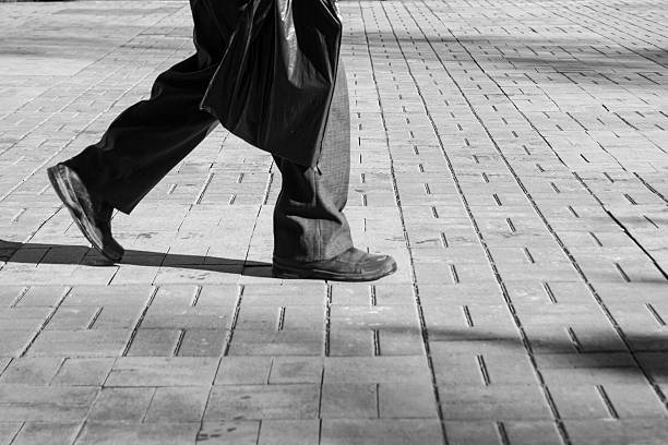 A man walks alone with old shoes and a plastic carrier bag