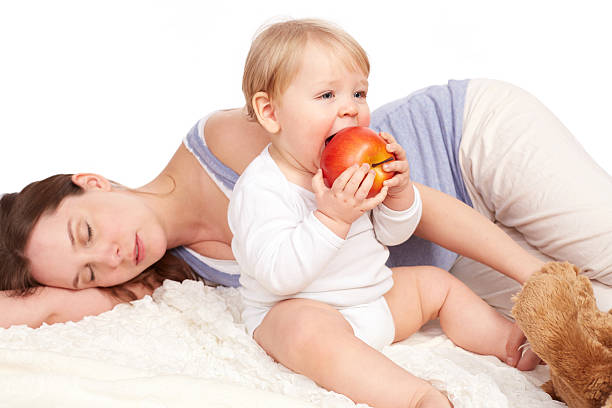 Young pregnant woman holding an apple, healthy pregnancy. Isolated on black background. Studio shot.