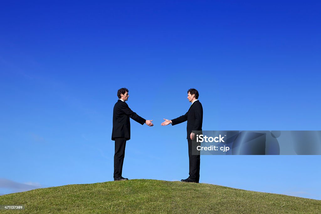 Businessmen Greeting Each Other on a Hilltop Two businessmen greeting each other with a traditional handshake. (Same person.) See link below for same shot but with hands connected... Abstract Stock Photo