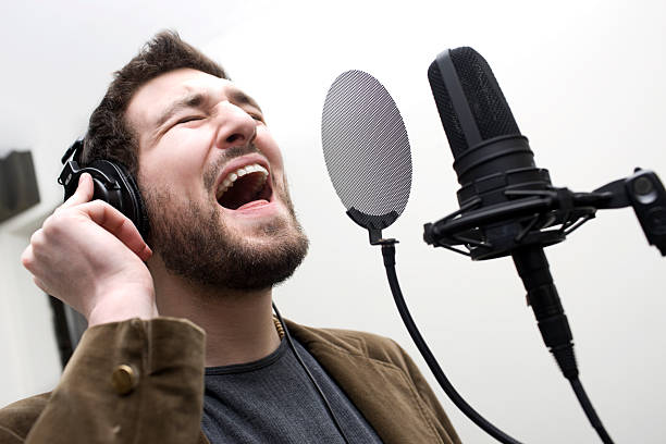 istock Caucasian Young Man in Headphones Singing into Studio Microphone 471138027