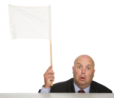 A man waving a white flag behind desk.