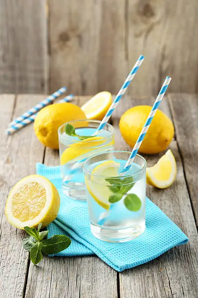 Fresh lemonade with lemon on grey wooden background