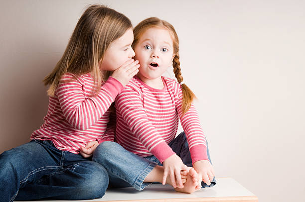 Two Little Girls Whispering Surprising Secrets