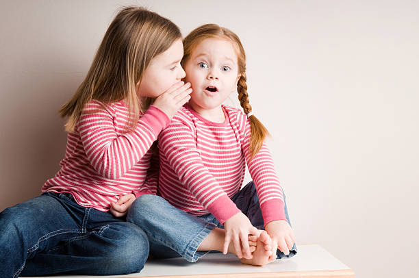 Two Little Girls Whispering Surprising Secrets stock photo