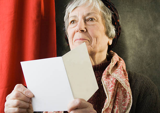 An elderly woman pleased with a greetings card.