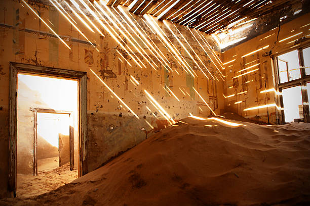 Abandoned House Full of Sand in Kolmanskop in Namibian Desert This is an image of an abandoned old house in the ghost town of Kolmanskop in Namibian desert. Sunlight falls through the holes in the roof, the doors are broken, and the rooms are full of sand. The image could also be used for various concepts related to home improvement and renovation. kolmanskop namibia stock pictures, royalty-free photos & images