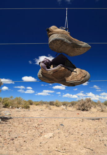 A pair of well-used hiking shoes, hung from a fence in the Argentine Pampas (desert).