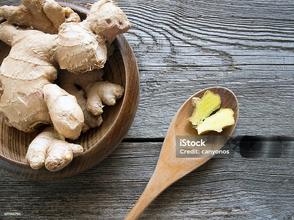 Overhead shot of ginger on dark wooden background Ginger in a bowl on rustic wooden background with slice on a ladle Ginger - Spice Stock Photo