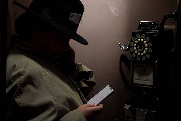 Calling In The Story A 1940's/50's reporter in a phone booth phoning in his story.  Small tag on his fedora says "PRESS". film noir style photos stock pictures, royalty-free photos & images