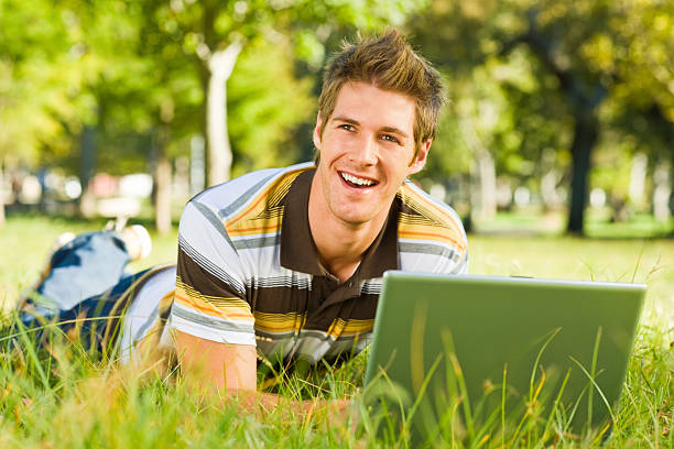 istock Happy young man using laptop at park 471145915