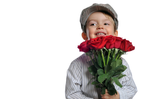 Adorable young boy holding a dozen roses. He has a nervous smile and is looking off to the side. Studio image photographed on a white background.