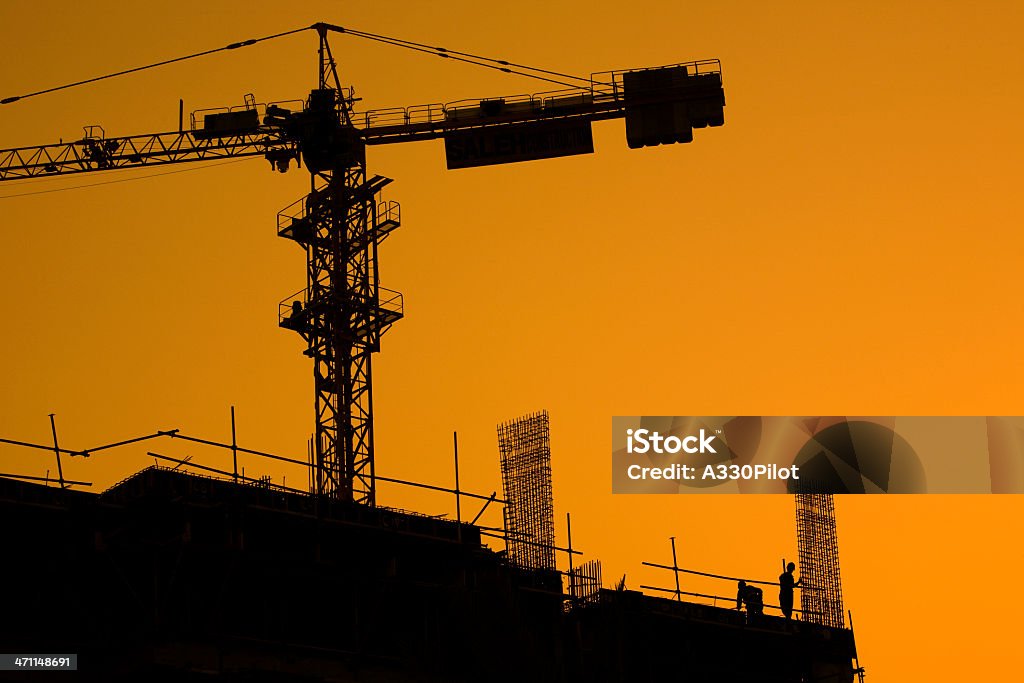 Sunset Construction Workers at a construction site at sunset. Architecture Stock Photo