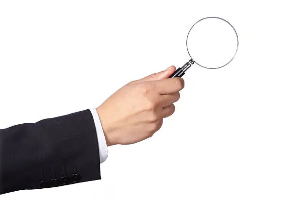 A hand of a businessman holding a magnifying glass, isolated on white background.