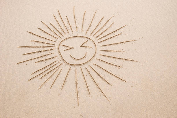 Sand drawing of sun with happy face and long streaming shafts of light