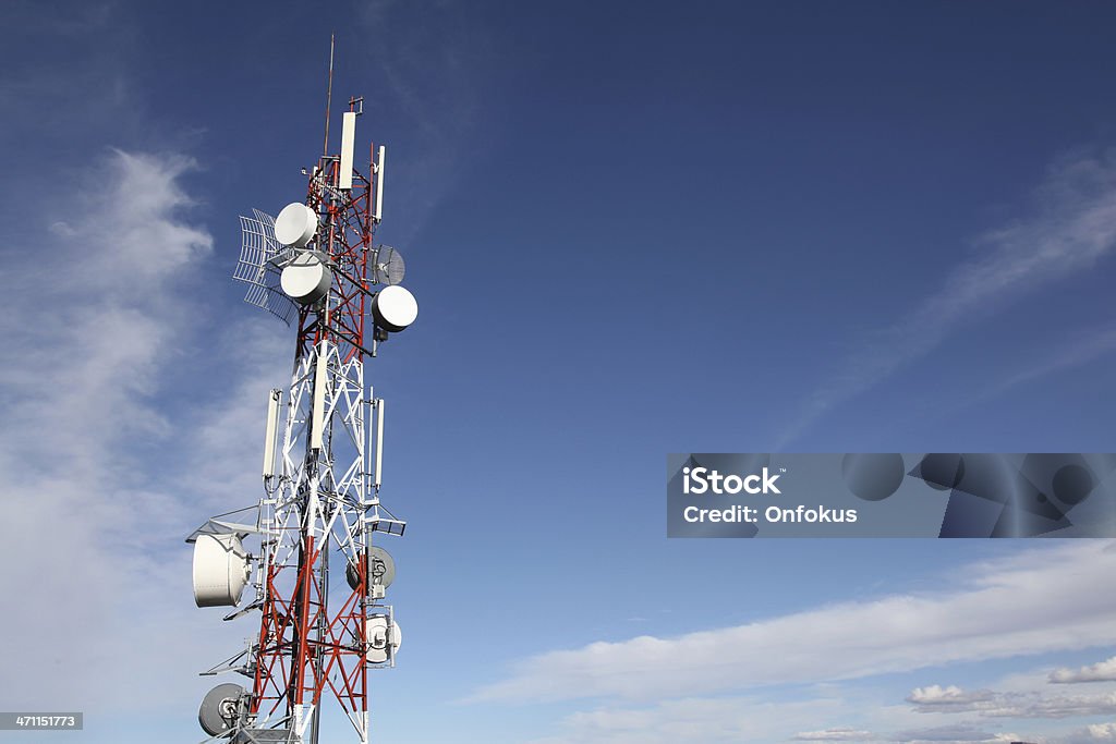 Communication Antennas DSLR picture of Communication Tower and Antennas on a blue sky background. The tower is white and red, microwave and satellite dishes are pointing in many directions. Mobile Phone Stock Photo