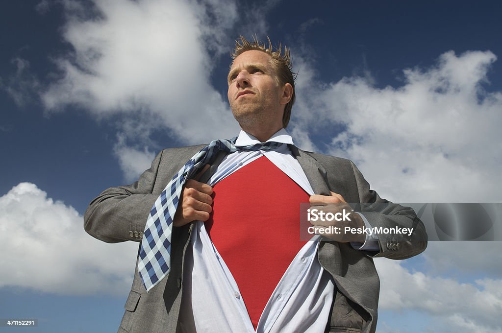 Serious Superhero Businessman Standing Outdoors against Bright Sky Serious businessman man pulling open his suit to reveal bright red shirt of inner superhero at blue sky 20-29 Years Stock Photo