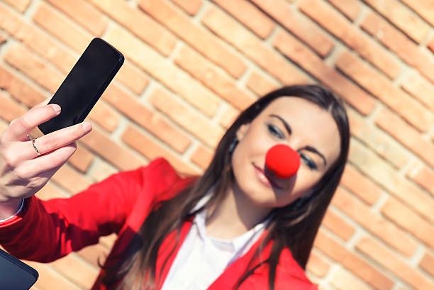 donna d'affari con clown naso e fanno selfie - curtain red color image clown foto e immagini stock