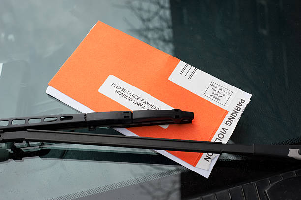 Parking violation ticket under a windshield wiper stock photo