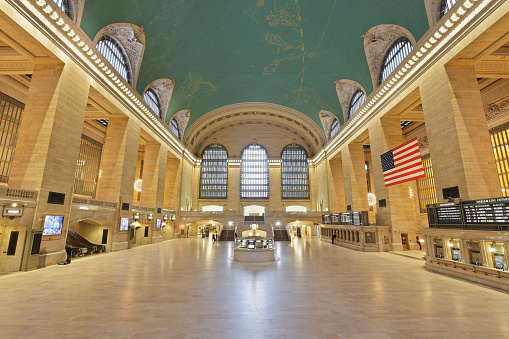 The main concourse of the Grand Central Station is a monumental space and usually filled with crowds. The American flag was hung a few days after the September 11 attacks. The main information booth is in the center of the concourse with a  clock on top designed by Henry Bedford.