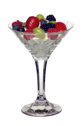 A cocktail glass full with fresh fruit salad and cream, isolated on white with clipping path.