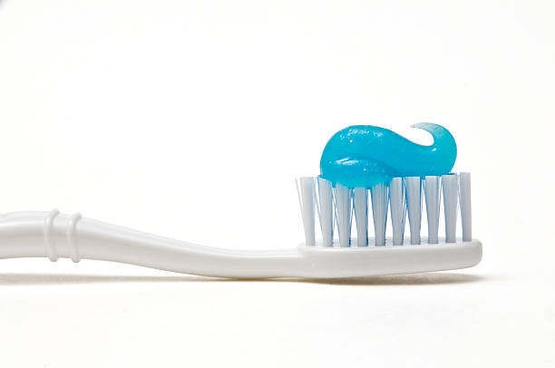 White toothbrush with blue swirl of toothpaste Toothbrush and toothpaste toothbrush photos stock pictures, royalty-free photos & images
